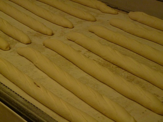 Avant d'être mises au four, le boulanger entaille les baguettes avec une lame de rasoir.