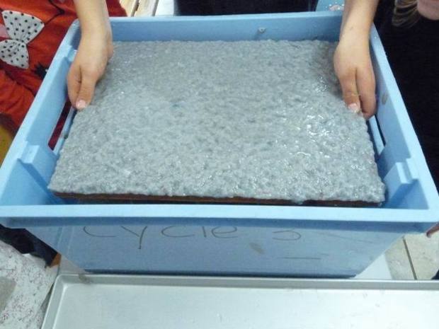 On verse la pâte à papier dans un grand bac et on y plonge le tamis avant de le remonter. On verse la pâte à papier dans un grand bac et on y plonge le tamis avant de le remonter.