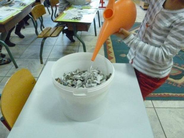 On commence par déchirer  des petits bouts de papier usagés et on ajoute de l'eau chaude. On commence par déchirer  des petits bouts de papier usagés et on ajoute de l'eau chaude.