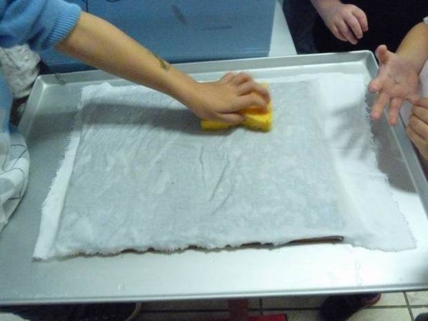 On étale un tissu sur le tamis et on tapote avec une éponge pour retirer le plus d'eau possible. On étale un tissu sur le tamis et on tapote avec une éponge pour retirer le plus d'eau possible.